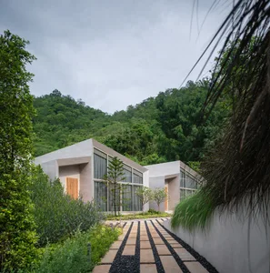 Modern residential building with large windows and a lush green landscape.