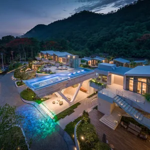 A modern residential exterior featuring a concrete poolside with a glass roof and surrounding greenery.