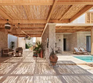A modern residential patio featuring a concrete floor and a swimming pool surrounded by a wooden pergola structure.