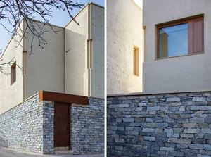 Modern house exterior featuring a stone foundation and stucco walls.