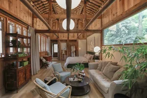 A spacious rustic living room featuring hardwood floors, exposed wooden beams, and a comfortable seating area with a sofa and