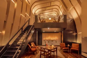 Industrial-style restaurant interior with wooden furniture and exposed ceiling beams.