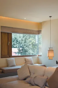 A minimalist living room with beige furniture and a large window.
