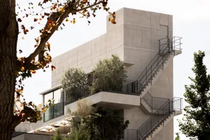 Modern building exterior made of concrete with trees and stairs.