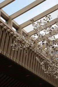 Ceramic branches hanging from a modern architectural space with skylights.