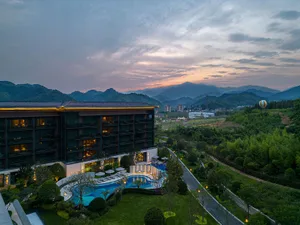 A modern hotel resort with a pool and hot air balloon in the background.