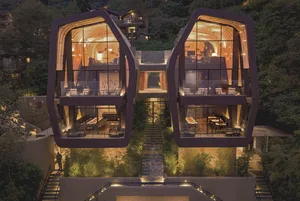 A modern residential building with glass facades, illuminated at night.