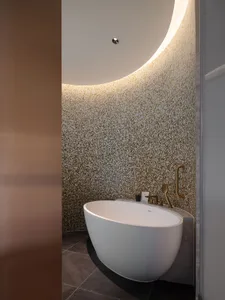 Modern minimalist bathroom with a tile floor, white bathtub, and geometric mosaic tile wall.