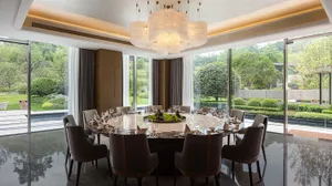 Modern dining room with a large round table set for a meal, featuring contemporary furniture and a minimalist design aestheti