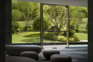 A modern hotel lobby featuring glass, concrete, and greenery