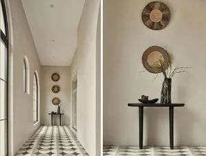 A modern interior corridor featuring concrete walls and patterned tiles with decorative woven baskets hanging on the walls.