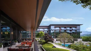 Modern residential building exterior with glass and concrete materials and landscaping.