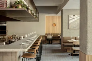 A modern restaurant interior with concrete walls and wooden seating