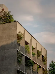 A modern building with green plants growing out of its balconies.