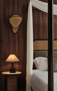 A cozy bedroom with wooden paneled walls, a canopy bed, and a table lamp.