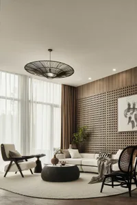 A modern living room with neutral decor, featuring a round black coffee table, white sectional sofa, and large windows with s