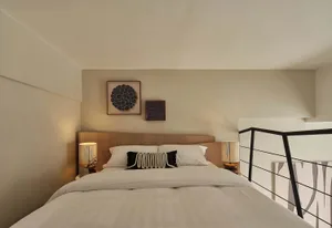 A modern bedroom features minimalist lighting and a comfortable bed with white bedding and black and white accent pillows.