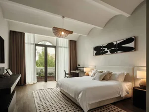 A minimalist bedroom featuring white fabrics on the bed and a wooden floor.