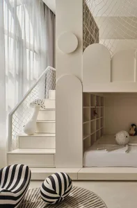 A minimalist children's bedroom with white bunk beds and stairs leading to a loft area.