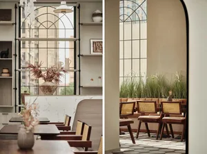 Industrial-style cafe interior with wooden chairs and metal accents, featuring a display shelf with vases and plants.