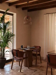 Minimalist interior dining area with wooden furniture, leather chairs, and a woven lampshade.
