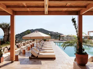 Outdoor seating area with wooden pergola and striped fabric lounge chairs at a resort