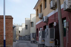 A city street with buildings incorporating concrete exteriors and airconditioning units attached to the facade.
