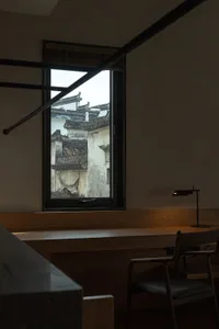 Minimalist interior space featuring a wooden window with a view of tiled roofs outside.
