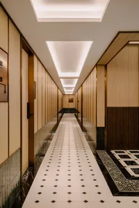 Modern hotel hallway featuring marble walls and a wooden floor.