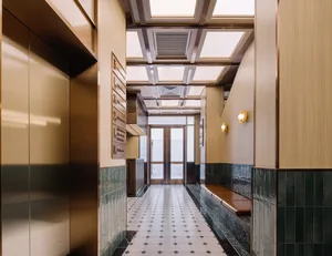 Modern interior design featuring a metal corridor with glass doors and wooden benches.
