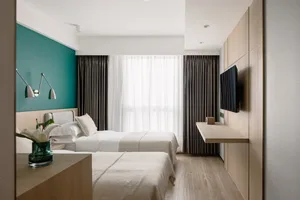 Modern minimalist bedroom with twin beds, teal accent wall, and wooden flooring.
