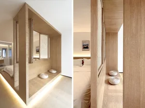 Modern minimalist bedroom with light wood walls and flooring, featuring a bed with white bedding and a built-in window seat w