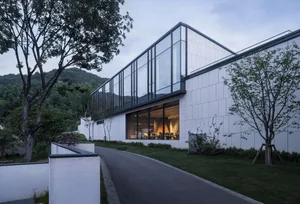 A modern residential building with glass walls and white tiled exteriors.