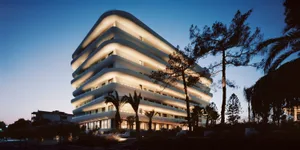 A modern apartment building with concrete exterior and illuminated balconies.