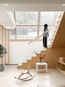 A modern white staircase with wood steps and a glass railing in a minimalist interior design setting.