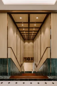 An elegant, tall staircase with wooden panels and marble flooring leading upwards.