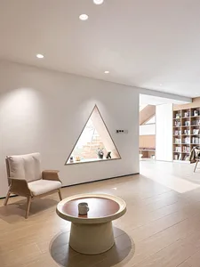 Modern living room with a triangle window and wooden furniture.