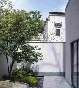 A minimalist building exterior showcasing a white concrete wall and a traditional-style window.