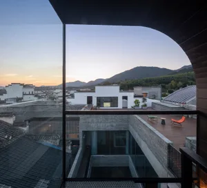 Modern brick building with glass windows and outdoor seating area in a mountainous landscape.