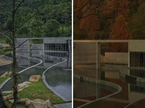 A modern building with a curved concrete structure reflected in a pool of water.
