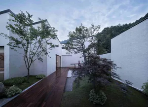 A modern house with a white exterior featuring wooden pathways and greenery.