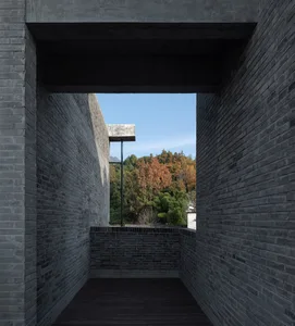 A modern interior space featuring brick walls and a view of a forested area through an open doorway.