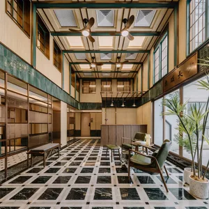 A modern lobby with marble flooring and green accents, featuring seating areas and large windows.