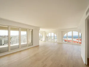 Modern apartment living room featuring hardwood flooring and large glass windows.