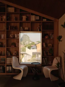 A cozy indoor library with wooden shelves and concrete floor, featuring a wooden bench and bookshelves filled with books, loo