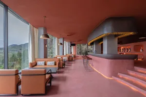 Modern minimalist restaurant bar with concrete walls and seating, large windows overlooking the landscape.