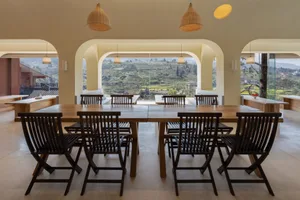 A spacious cafeteria with wooden furniture and large windows providing a scenic view of the hills.