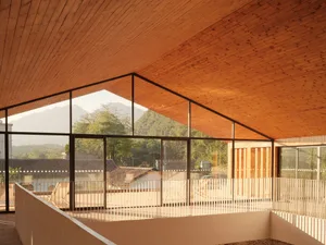 Modern house with a wooden penthouse featuring a spacious balcony overlooking green trees and mountains.