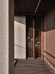 A modern wooden lattice entrance with a stone wall.