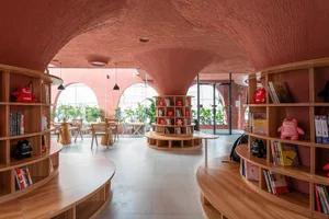 現代圖書館室內，配有木質書架、圓桌與紅色拱門。